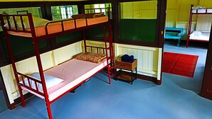 A bunk bed room with a wooden frame, a small wooden table, and a bench. - Korovou Homestay Fiji (Naduri)