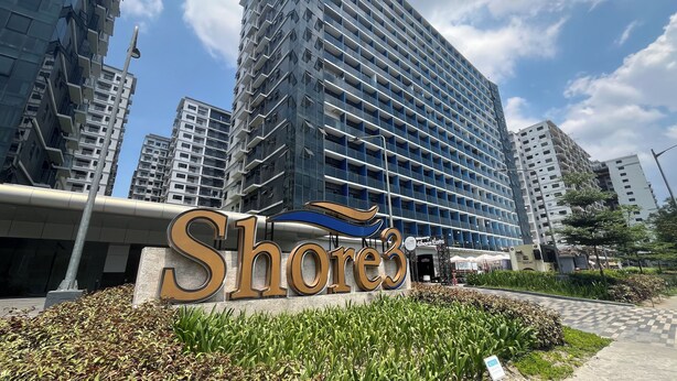 Un bâtiment moderne, reconnaissable à son grand panneau « Shore3 », entouré d’immeubles résidentiels de grande hauteur.