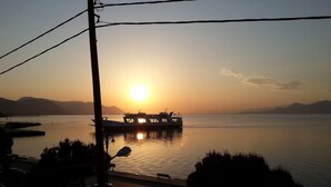 Un coucher de soleil sur un lac paisible, avec un bateau amarré près du rivage.