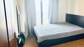Une chambre à coucher avec un lit, une armoire, une fenêtre avec des rideaux et un balcon.
