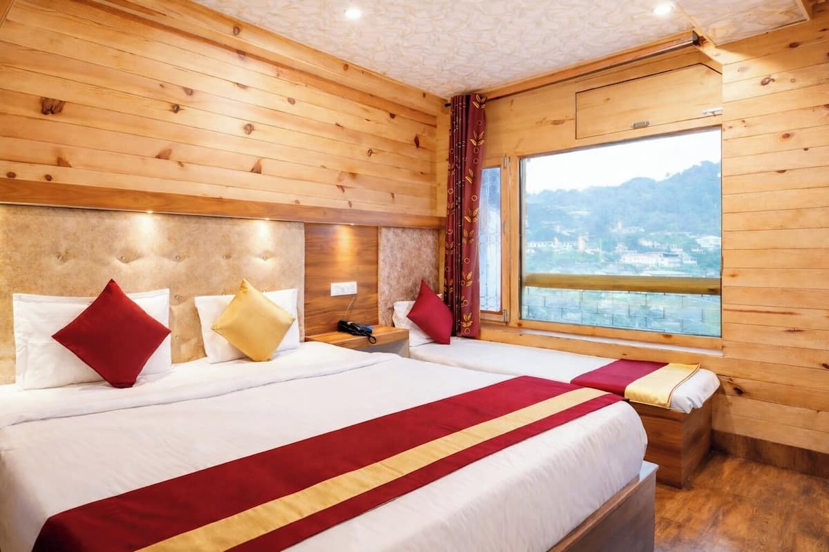 Habitación de hotel con dos camas, paredes de madera, una ventana con vistas y un corredor de cama rojo y dorado.
