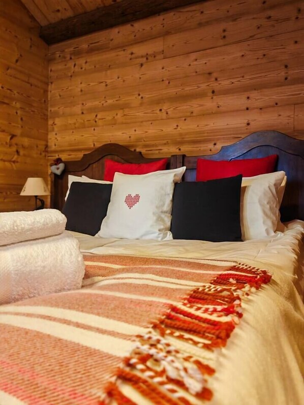 Un dormitorio tipo cabaña de madera con cama, almohadas y manta.