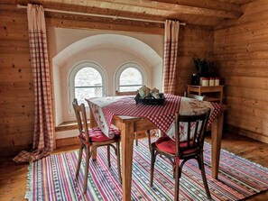A cozy dining area with a wooden table and chairs, a checkered tablecloth, and a colorful striped rug. - Cozy Chalet w/Fireplace, Patio & Barbecue. Pet Friendly! (Gex)