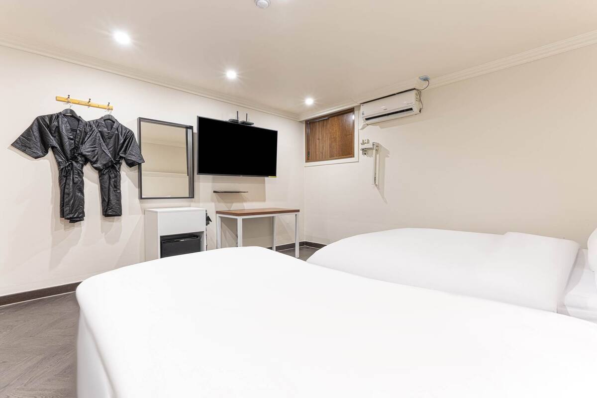 A hotel room with a bed, a desk, a chair, a TV, and a mirror.