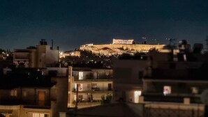 A nighttime view of a cityscape with a prominent ancient amphitheater illuminated in the background. - Athens Heart Acropolis Balcony (Athens)
