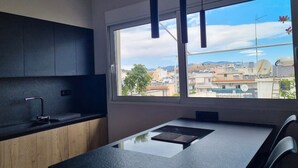 A modern kitchen with a large window, a black countertop, and wooden cabinets. - Athens Heart Acropolis Balcony (Athens)