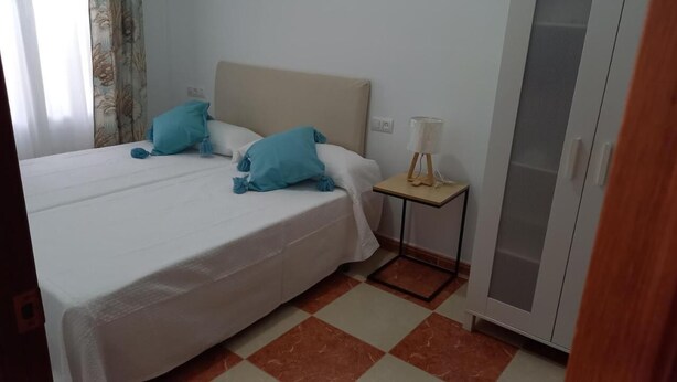 A hotel room with a bed, two pillows, a bedside table with a lamp, and a wardrobe. - Andalusia Tourist Accommodation (Córdoba)