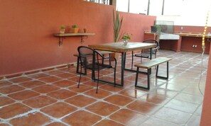 Une terrasse extérieure avec une table et des chaises, un banc et des plantes en pot.