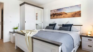 Ein Schlafzimmer mit Bett, Nachttischen, einem Kleiderschrank und einem Bild an der Wand.
