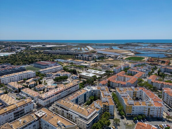 Vista aerea di una città costiera caratterizzata da un'intensa urbanizzazione, con edifici residenziali a più piani e un porto turistico.