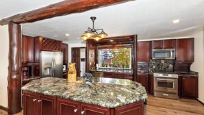 A kitchen with a large island, wooden cabinets, stainless steel appliances, and a unique bear sculpture.