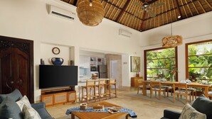 Una sala de estar con televisión, sofá, mesa de centro y comedor con sillas y mesa.