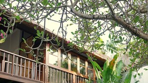 Una casa de dos pisos con balcón, piscina y abundante vegetación.