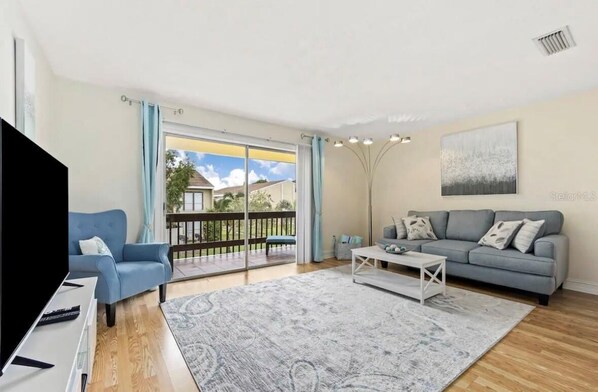 En moderne stue med tv, sofa og balkon med udsigt.