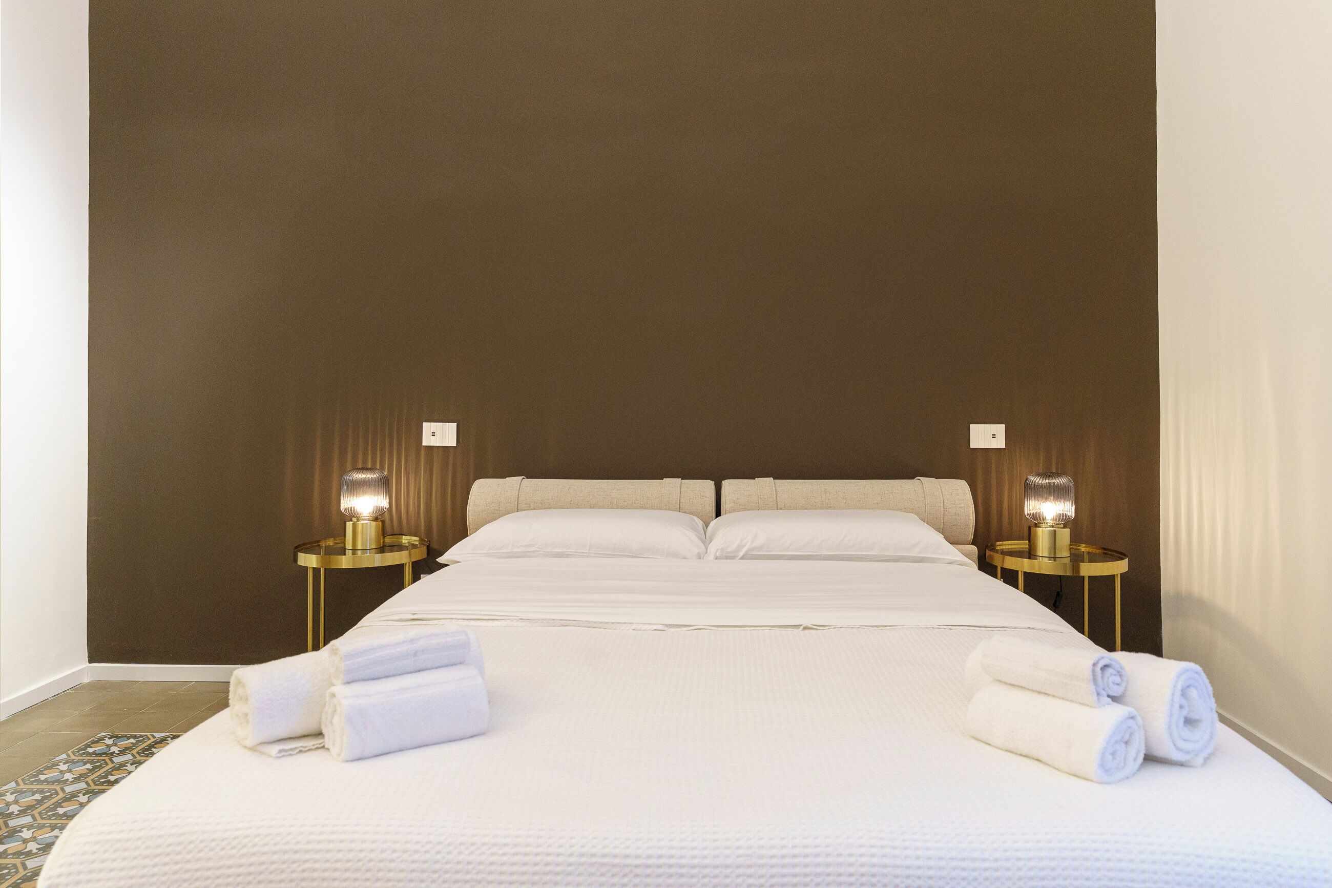 Une chambre d’hôtel avec un grand lit, deux tables de chevet avec des lampes et des serviettes soigneusement pliées sur le lit.