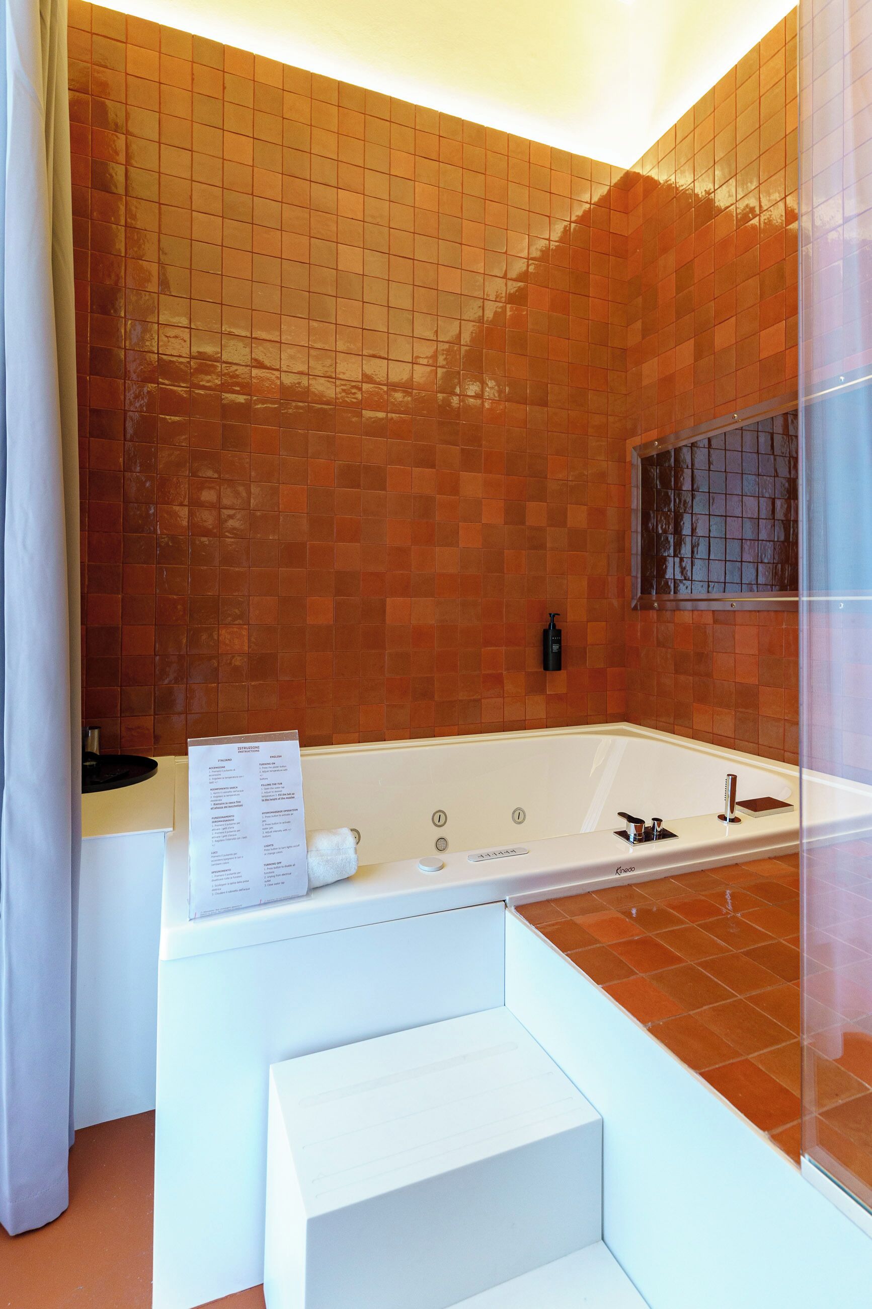 Une salle de bain moderne avec une grande baignoire, un banc blanc et un mur recouvert de carreaux.
