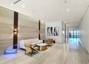 A modern interior with a sofa, chairs, and a small table. - Bloomfields 1BR Azizi Farhad Burj View (Dubai)