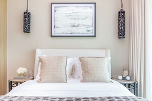 A neatly made bed with two pillows, a framed abstract painting above, and two hanging lamps on either side. - Bloomfields 1BR Azizi Farhad Burj View (Dubai)
