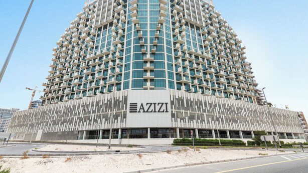 A multi-story AZIZI hotel with a modern architectural design, featuring a prominent entrance and a series of balconies. - Bloomfields 1BR Azizi Farhad Burj View (Dubai)