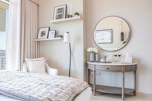 A bedroom with a bed, a bedside table with a mirror, and a window with curtains. - Bloomfields 1BR Azizi Farhad Burj View (Dubai)