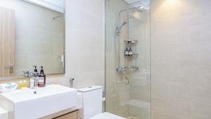 A modern bathroom with a glass-enclosed shower, a white sink, and toiletries on the counter. - Bloomfields 1BR Azizi Farhad Burj View (Dubai)