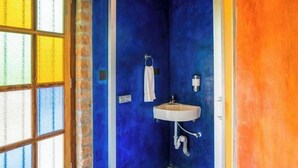 A bathroom with a blue wall, a white sink, and a towel hanging on the wall. - goSTOPS Pondicherry Near Auroville (Auroville)