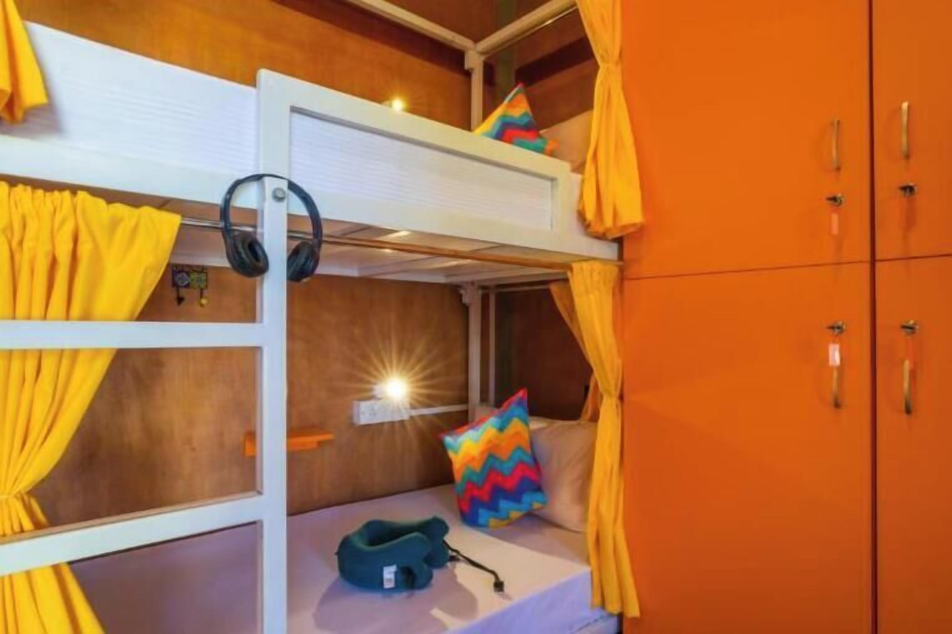 A bunk bed room with a headboard, a pillow, headphones, and a small pillow with a zigzag pattern.