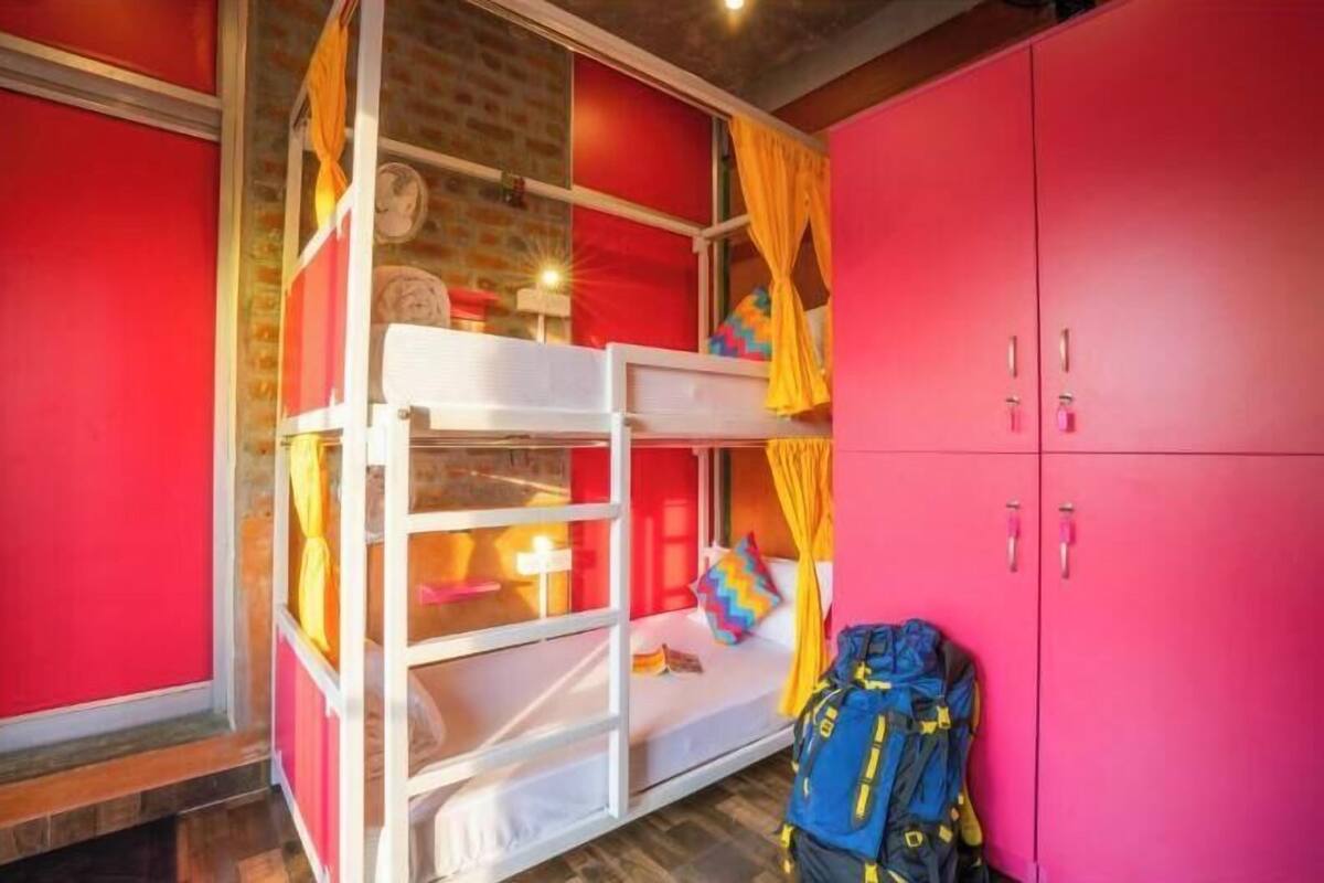 A room with a bunk bed, a pink wardrobe, and a blue backpack.