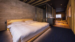 Et moderne hotelværelse med en stor seng, et træhovedgærde og en brusekabine med glasvægge.