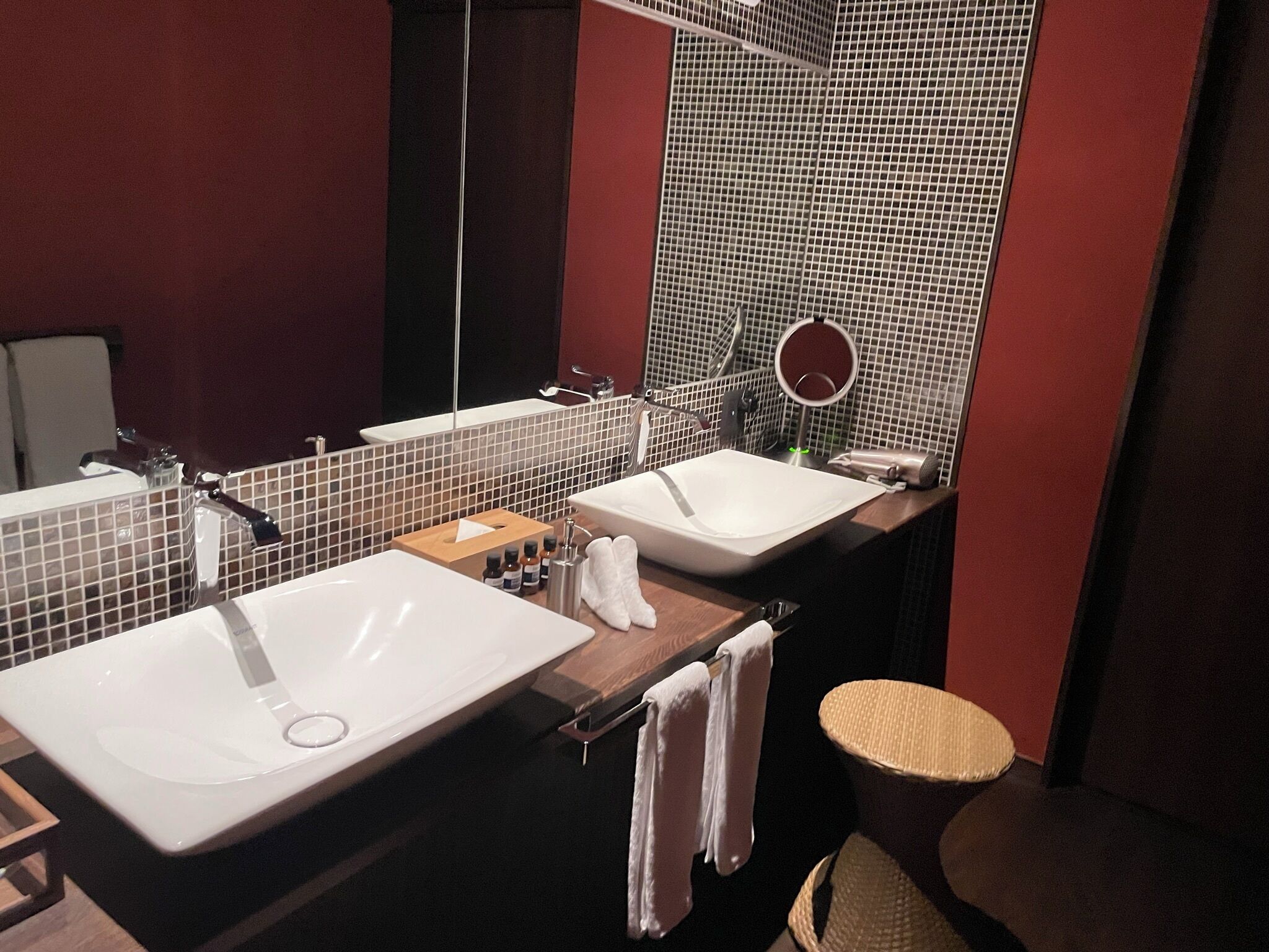 Un baño moderno con dos lavamanos, un espejo y un espejo redondo en la pared.