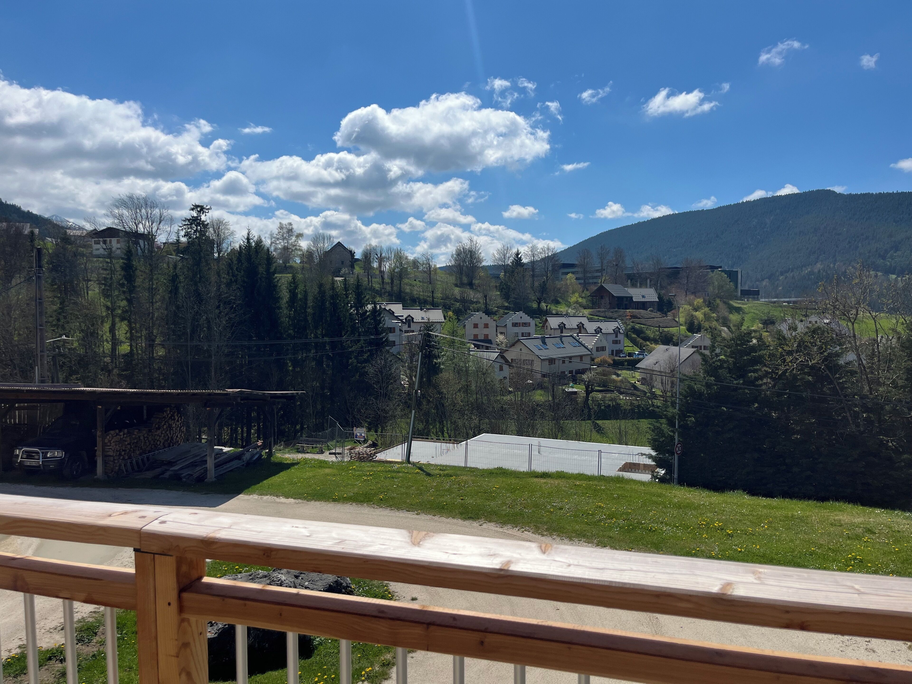 A view of a village with houses, a wooden fence, and a mountain in the background.