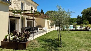 A stone building with a patio, outdoor seating, and a small tree. - Large renovated Mas provençale with swimming pool (Valréas)
