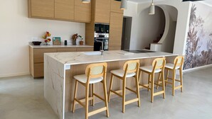 A modern kitchen with wooden cabinets, a marble island, and bar stools. - Large renovated Mas provençale with swimming pool (Valréas)
