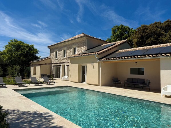 A poolside area with a swimming pool, lounge chairs, and a building with a tiled roof. - Large, renovated Provençal farmhouse with a pool (Valréas)