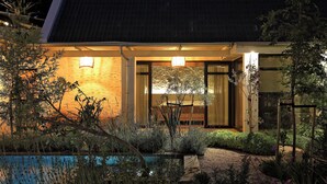 Een modern huis met een zwembad, omringd door weelderige begroeiing.