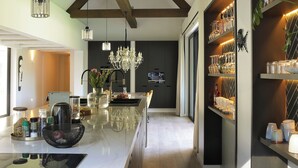 A modern kitchen with a marble countertop, wooden beams, and a central island with a sink and various kitchen items. - Bel Ombre Hills, 2200m2 luxury property in upper Constantia (Cape Town)