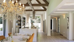 A spacious kitchen with a central island, wooden beams, and a chandelier. - Bel Ombre Hills, 2200m2 luxury property in upper Constantia (Cape Town)