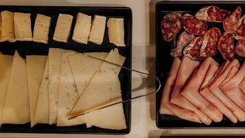 A variety of sliced meats and cheeses on trays.
