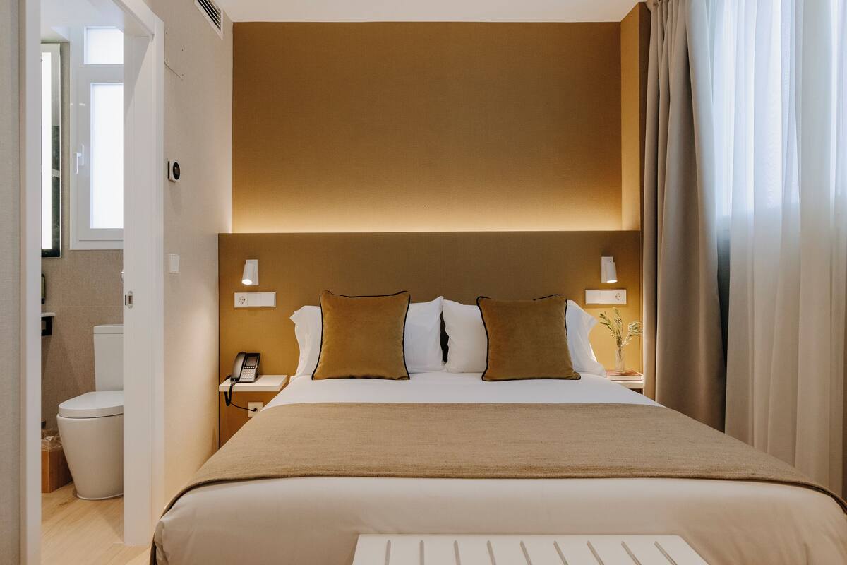 A hotel room with a large bed, bedside lamps, a telephone, and a nightstand.