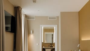 A modern hotel room with a large bed, a bedside table, a TV, and a bathroom visible through an open door. - Hotel PAX Atocha (Madrid)