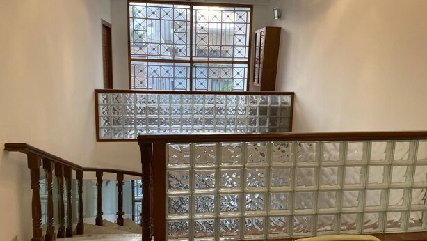 A staircase with a wooden railing and glass panels. - Mithra Homes (Hyderabad)