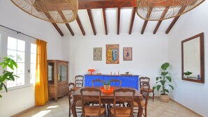 A dining area with a wooden table and chairs, a blue cabinet, and three wall-mounted artworks. - Les Salines holiday home 5 minutes from the beach (Le Grau-du-Roi)