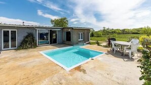 Ein Haus mit Swimmingpool, einer Terrasse mit Tisch und Stühlen sowie einem Garten.