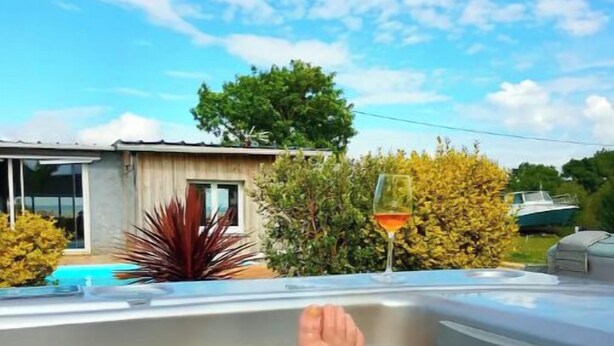 Eine Person entspannt sich in einer Hot Tub mit Blick auf ein Haus und ein Boot im Hintergrund.
