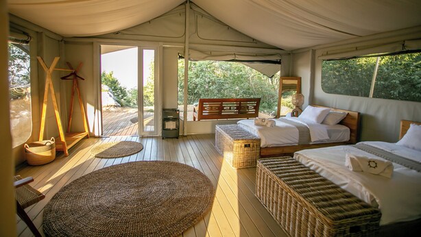 A tented accommodation with two beds, woven baskets, and a large woven mat. - Ashuma retreat center (Cetinje)