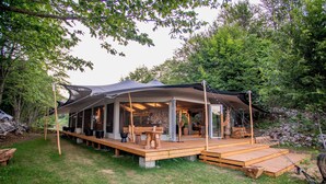 A modern outdoor structure with a covered patio, wooden deck, and built-in seating. - Ashuma retreat center (Cetinje)