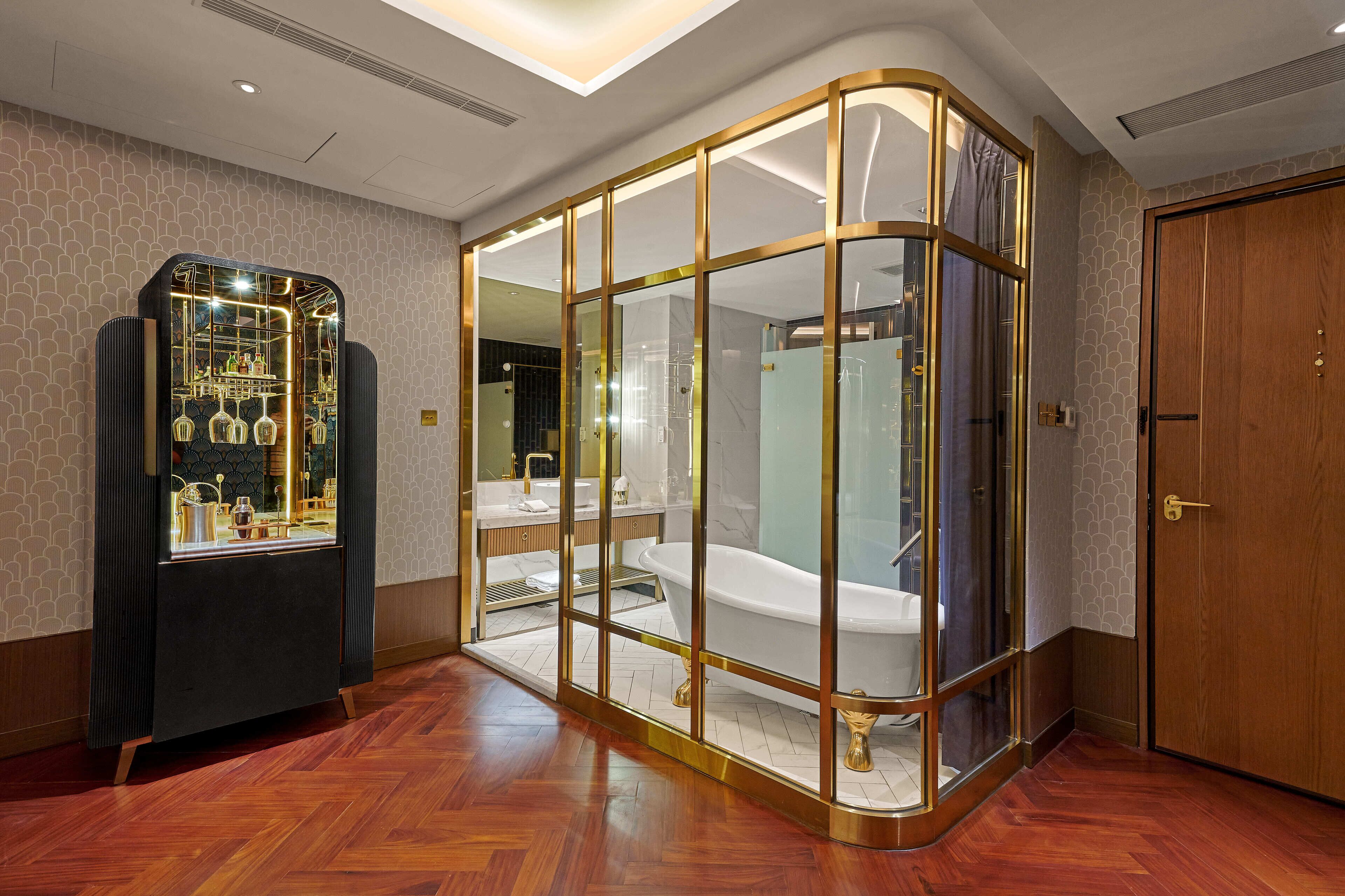 Une salle de bain moderne avec une baignoire sur pieds, un meuble-lavabo avec un encadrement en verre et un meuble d’exposition contenant des objets décoratifs.