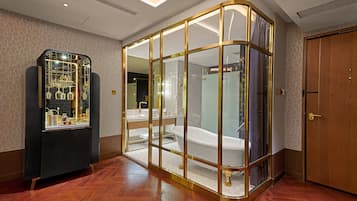 Un baño moderno con una bañera independiente, un tocador con mampara de vidrio y un aparador con objetos decorativos.