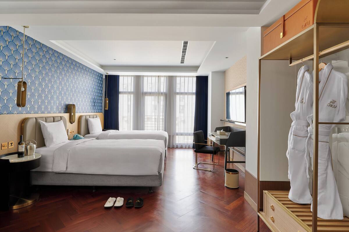 A hotel room with a large bed, a desk, a wardrobe, and a window with curtains.
