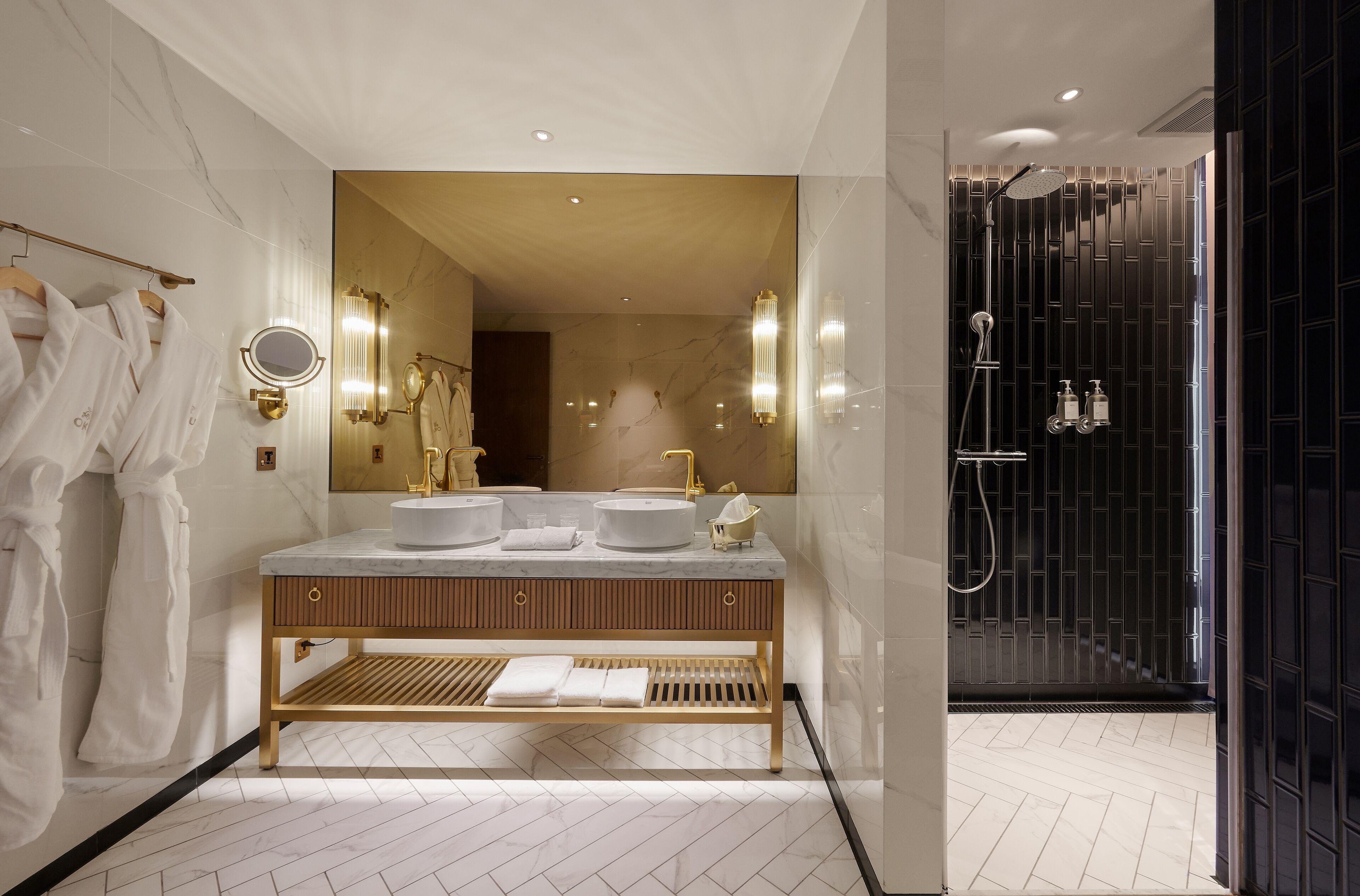 Un baño moderno con un espejo grande, dos lavamanos y una zona de ducha.